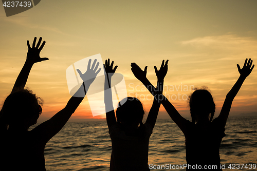 Image of Mother and children playing on the beach at the sunset time.