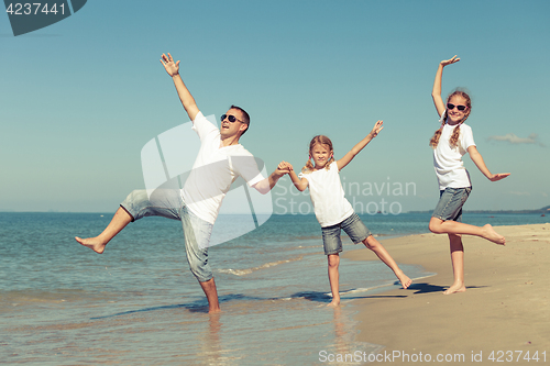 Image of Father and daughters playing on the beach at the day time.