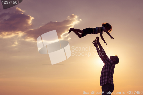 Image of Father and son playing on the beach at the sunset time.