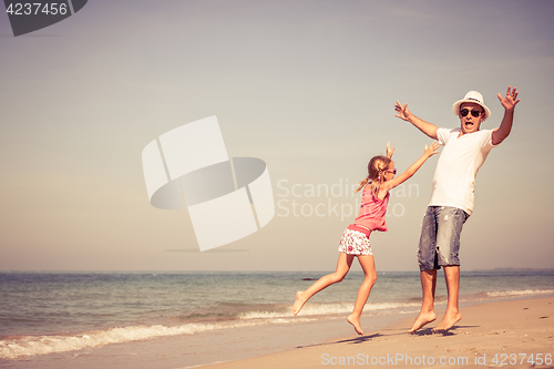 Image of Father and daughter playing on the beach at the day time. 