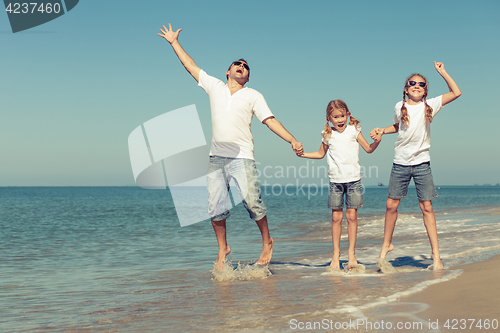 Image of Father and daughters playing on the beach at the day time.