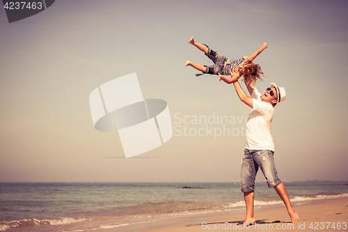 Image of Father and son playing on the beach at the day time.