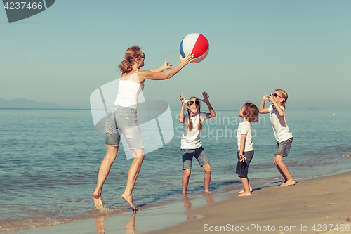 Image of Mother and  children playing on the beach.