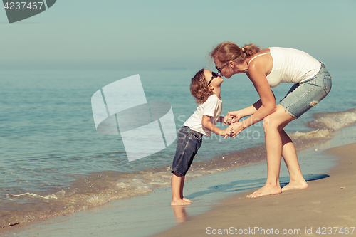 Image of Mother and son playing on the beach at the day time.