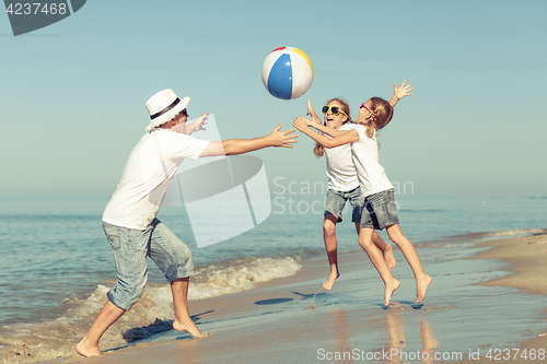 Image of Father and daughters playing on the beach at the day time.