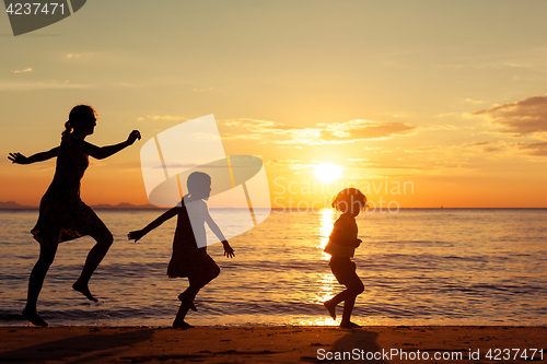 Image of Mother and children standing on the beach at the sunset time.