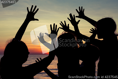 Image of Mother and children playing on the beach at the sunset time.