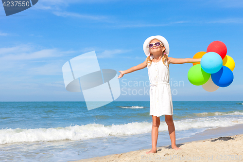 Image of Little girl with balloons standing on the beach