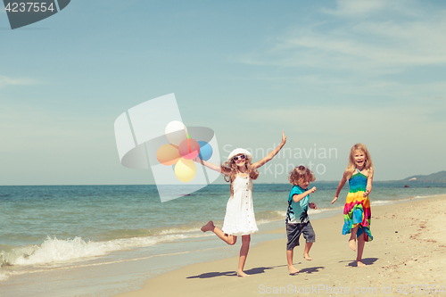 Image of Three happy children dancing on the beach at the day time