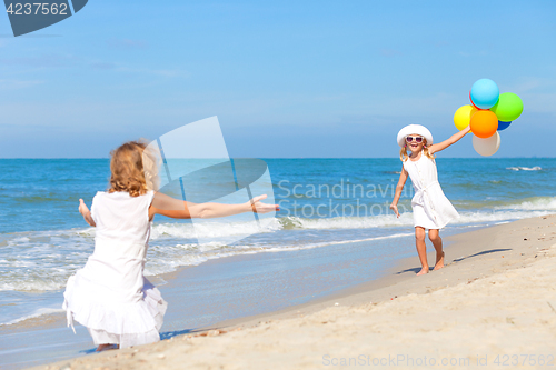 Image of Mother and daughter playing with balloons on the beach at the da