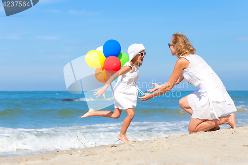 Image of Mother and daughter playing with balloons on the beach at the da