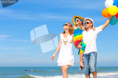 Image of Happy family playing  with balloons on the beach at the day time