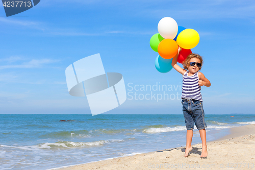 Image of Little boy with balloons standing on the beach