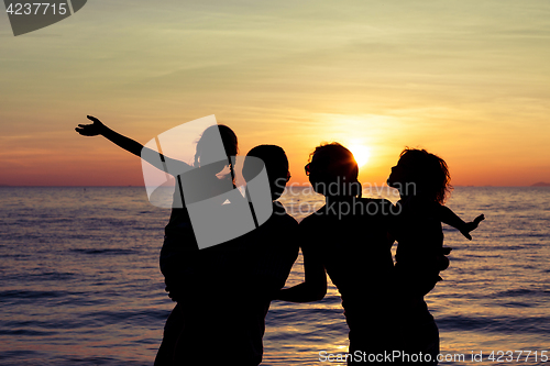 Image of Silhouette of happy family who playing on the beach at the sunse