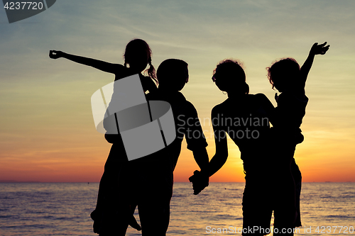 Image of Silhouette of happy family who playing on the beach at the sunse