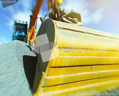 Image of excavator against blue sky. Toned image. Motion blur effect.