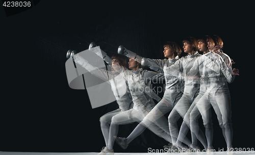 Image of Full-length portrait of woman wearing white fencing costume on black