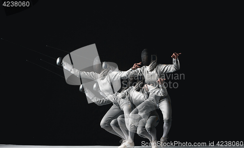 Image of Full-length portrait of woman wearing white fencing costume on black