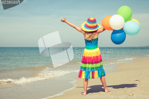 Image of Little girl with balloons standing on the beach