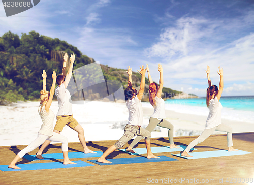 Image of group of people making yoga exercises on beach