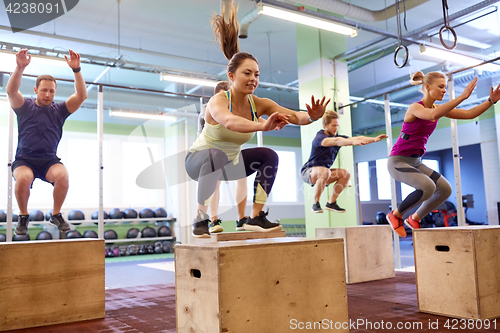 Image of group of people doing box jumps exercise in gym
