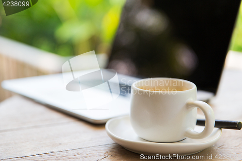 Image of close up of coffee cup and laptop on table