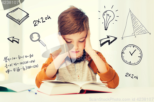 Image of student boy reading book or textbook at home