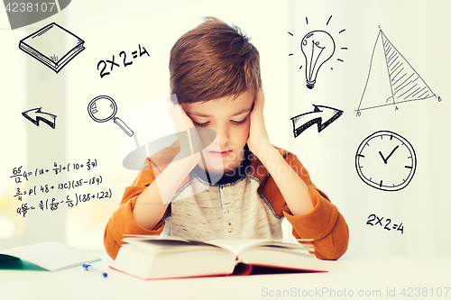 Image of student boy reading book or textbook at home