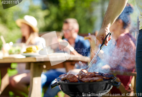 Image of man cooking meat on barbecue grill at summer party