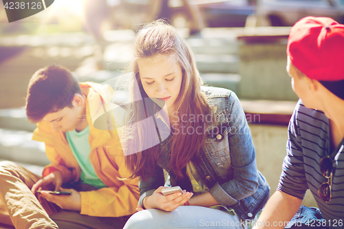 Image of teenage friends with smartphones outdoors