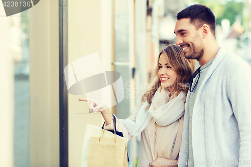 Image of happy couple with shopping bags at shop window