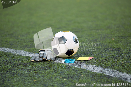 Image of ball, gloves, whistle and cards on soccer field