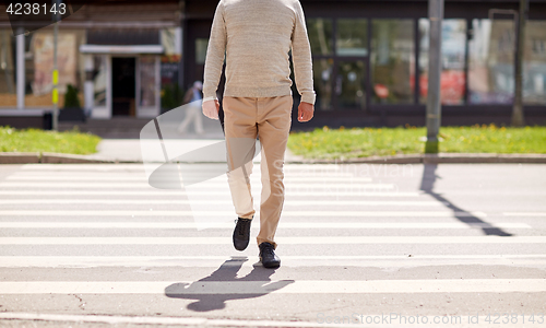 Image of senior man walking along city crosswalk