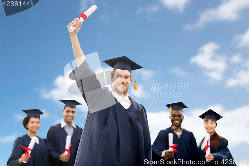 Image of students or bachelors with diplomas over blue sky