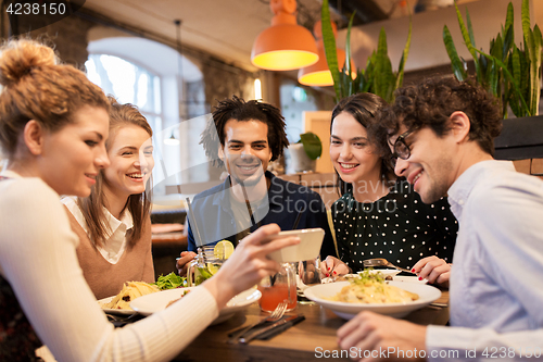 Image of friends with smartphone eating at restaurant