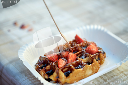 Image of waffle with strawberry on paper plate and fork