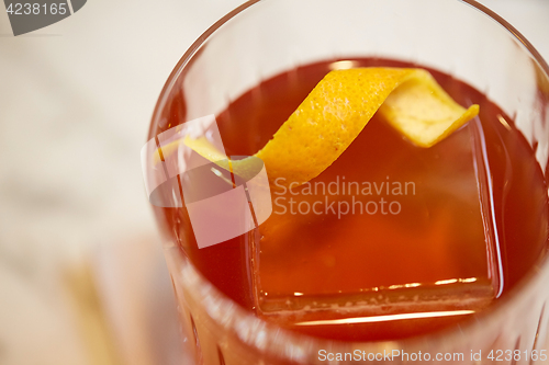 Image of close up of glass with orange cocktail at bar