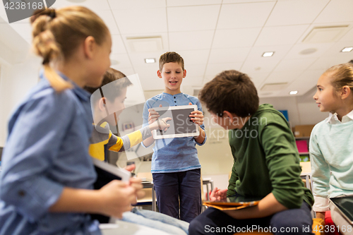 Image of group of happy children with tablet pc at school