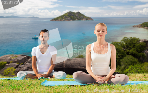 Image of happy couple doing yoga and meditating outdoors