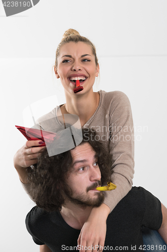 Image of couple in party hats blowing in whistle