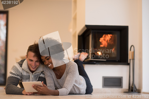Image of multiethnic couple using tablet computer on the floor