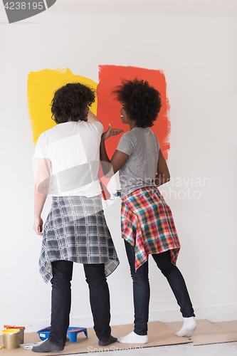 Image of multiethnic couple painting interior wall