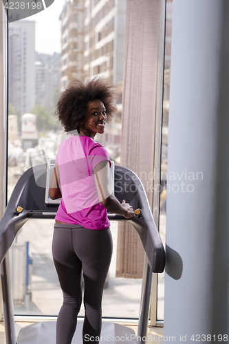 Image of afro american woman running on a treadmill