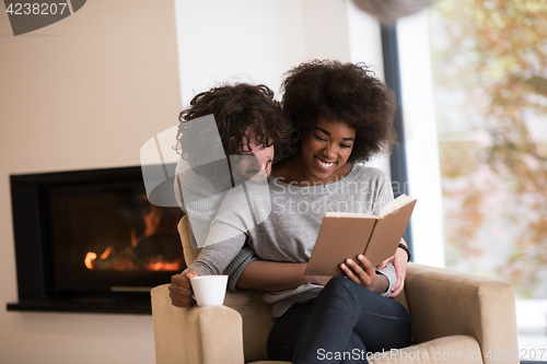 Image of multiethnic couple hugging in front of fireplace