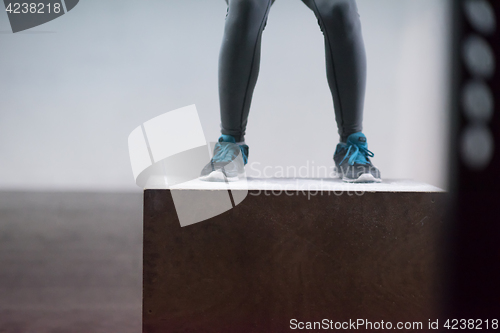 Image of black woman is performing box jumps at gym