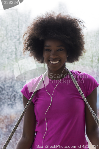 Image of portrait of young afro american woman in gym while listening mus