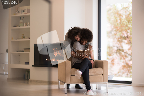 Image of multiethnic couple hugging in front of fireplace