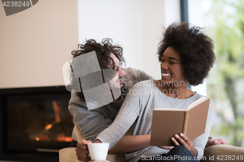 Image of multiethnic couple hugging in front of fireplace
