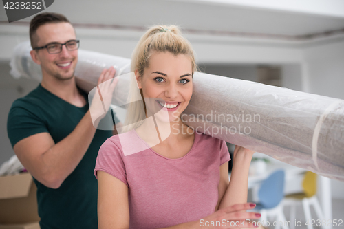 Image of couple carrying a carpet moving in to new home