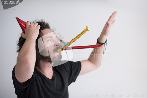 Image of Portrait of a man in party hat blowing in whistle